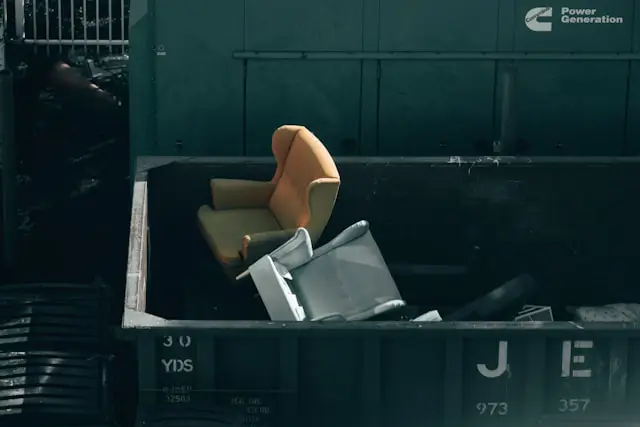 Professional furniture removal team loading furniture into a dumpster